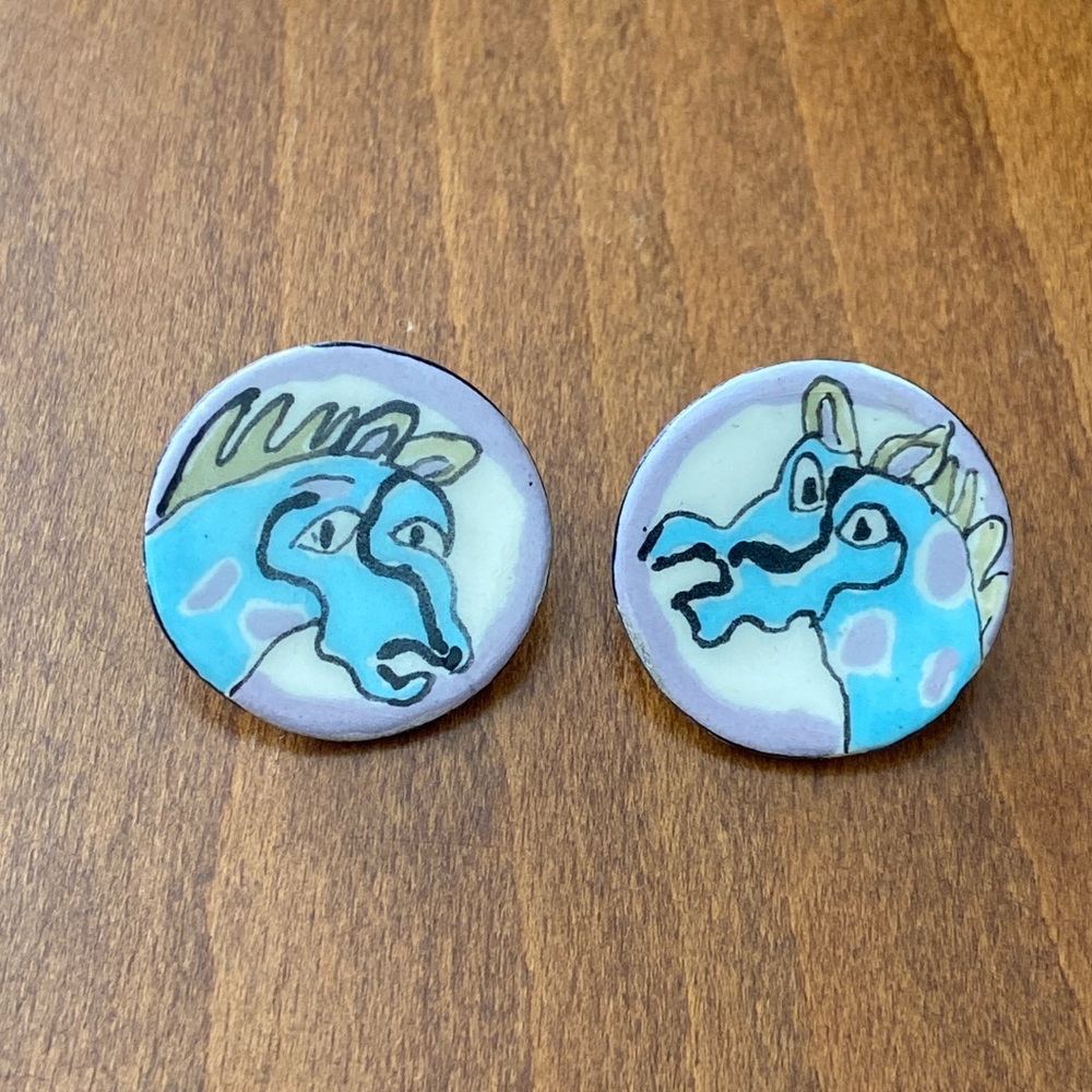 Jill Rosenwald ceramic earrings decorated with abstract horse heads. Blue/grey.